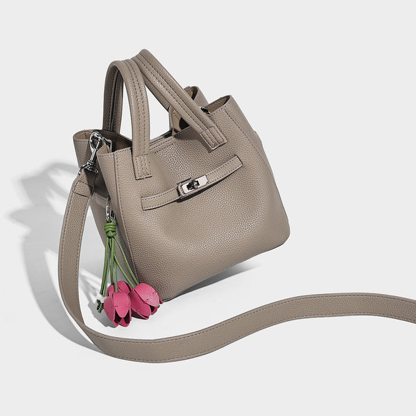 Small structured pebbled bucket tote bag with dual top handles, silver turn-lock front pocket, and detachable shoulder strap