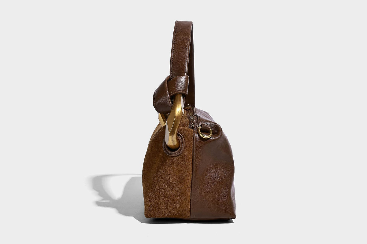 Kompakte Boston-Schultertasche in warmem Braun in Wildlederoptik mit glattem dunkelbraunem Besatz, übergroßen goldfarbenen Ringelementen und Reißverschluss oben