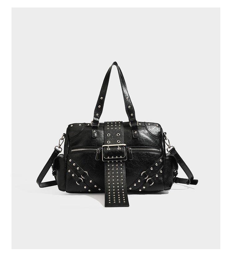 Structured pink leather-look satchel bag with gunmetal studded trim, rectangular buckle strap, dual top handles, and, detail