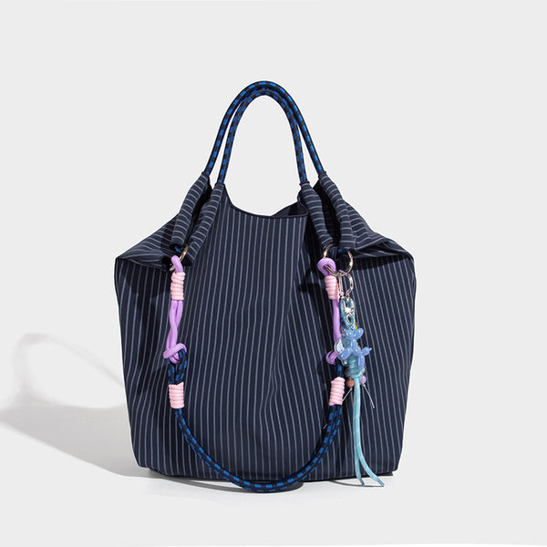 Slouchy pinstripe tote bag with braided rope handles, metal ring hardware, and colorful knotted rope charm, detail view 3