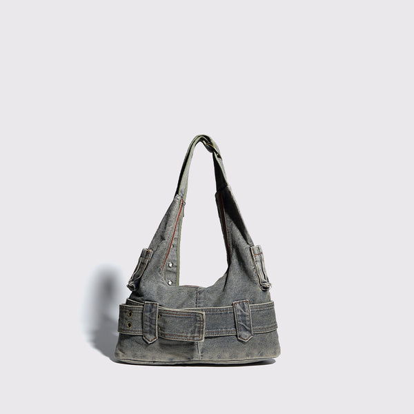 Washed faded denim hobo shoulder bag with wide brass-tone buckle belt panel, eyelet detailing, front zip pocket, and dual