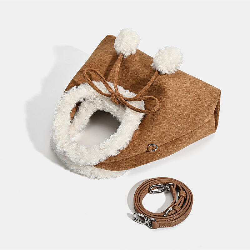 Trapezförmige Tasche aus karamellbraunem Wildlederimitat mit ovalem Henkel aus weißem Kunstfell, Pompon-Kordelverschluss und abnehmbarem Schulterriemen