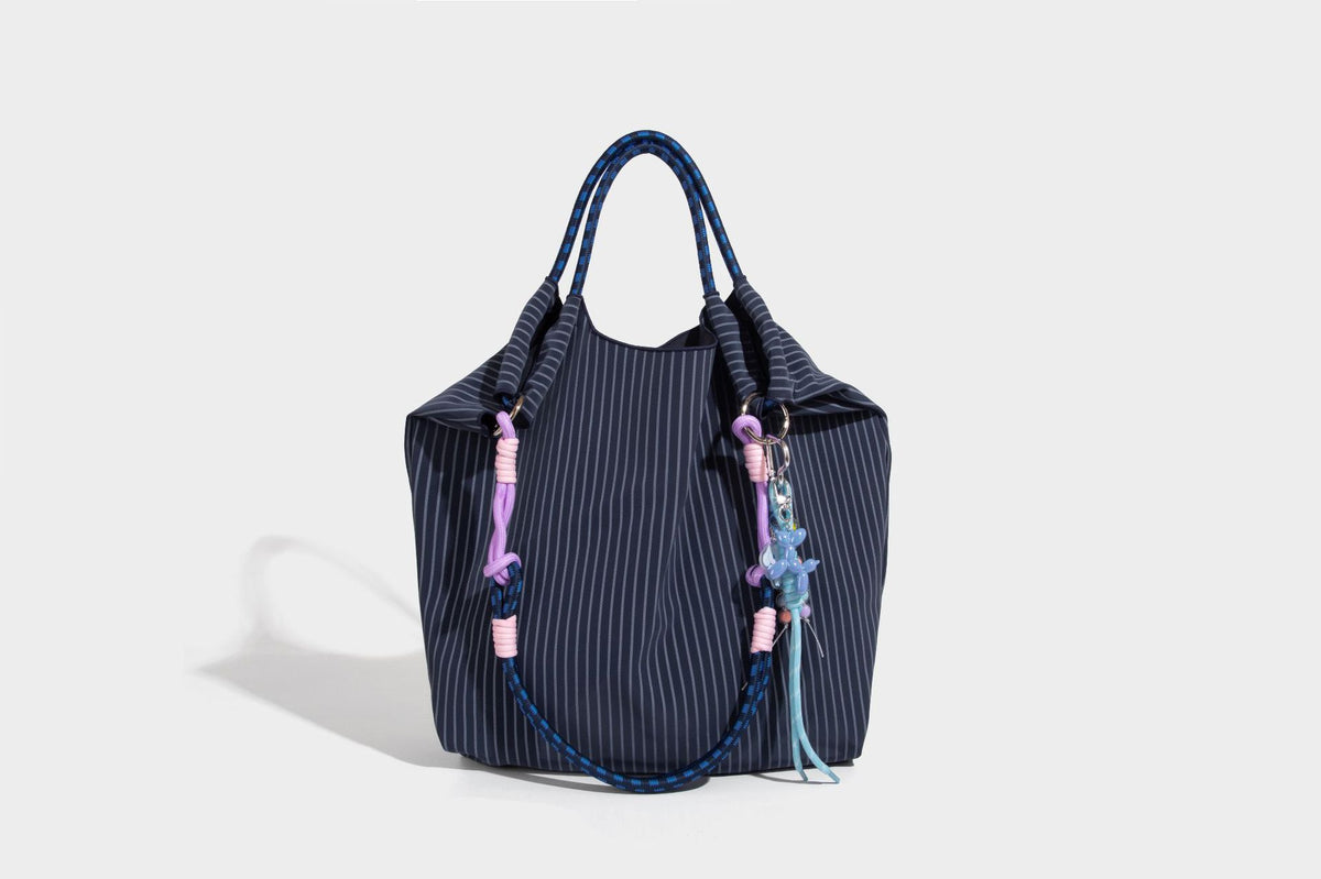 Slouchy pinstripe tote bag with braided rope handles, metal ring hardware, and colorful knotted rope charm, detail view 36