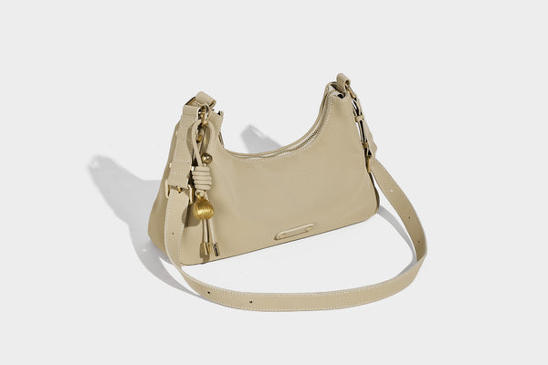Crescent hobo shoulder bag in pebbled leather-look finish with top zipper, adjustable strap, gold-tone ring hardware, and