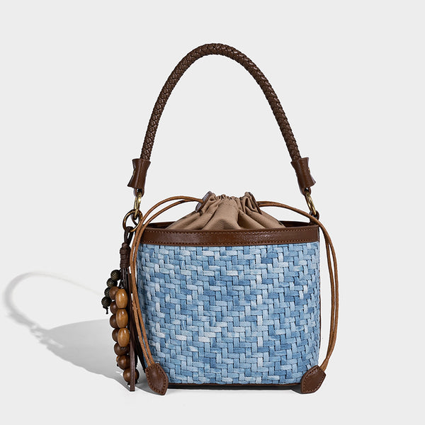 Small light blue woven bucket bag with brown leather-look trim, braided top handle, brass-tone ring hardware, drawstring