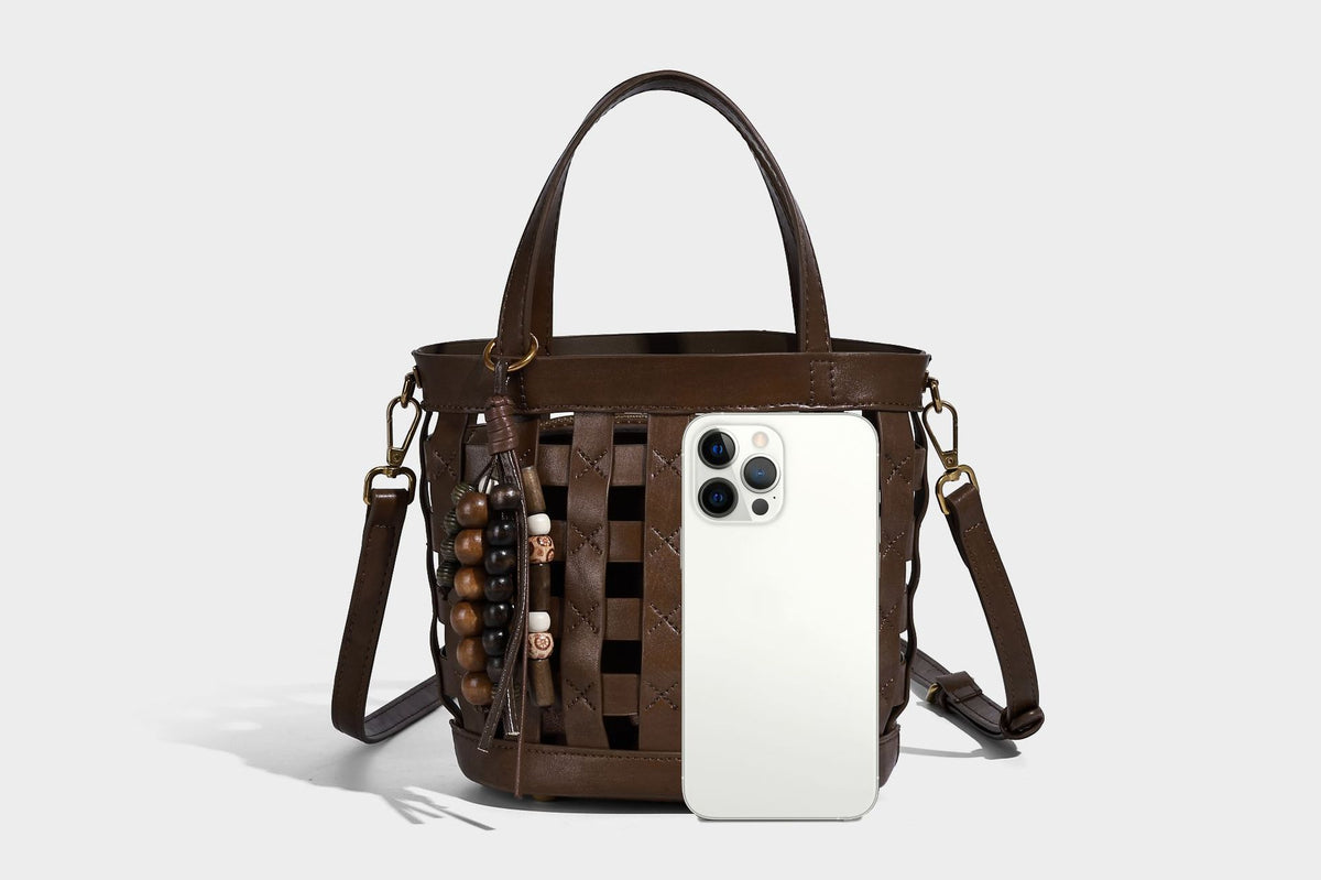 Small woven lattice bucket bag in brown leather-look finish with beaded tassel charm, dual top handles, and detachable