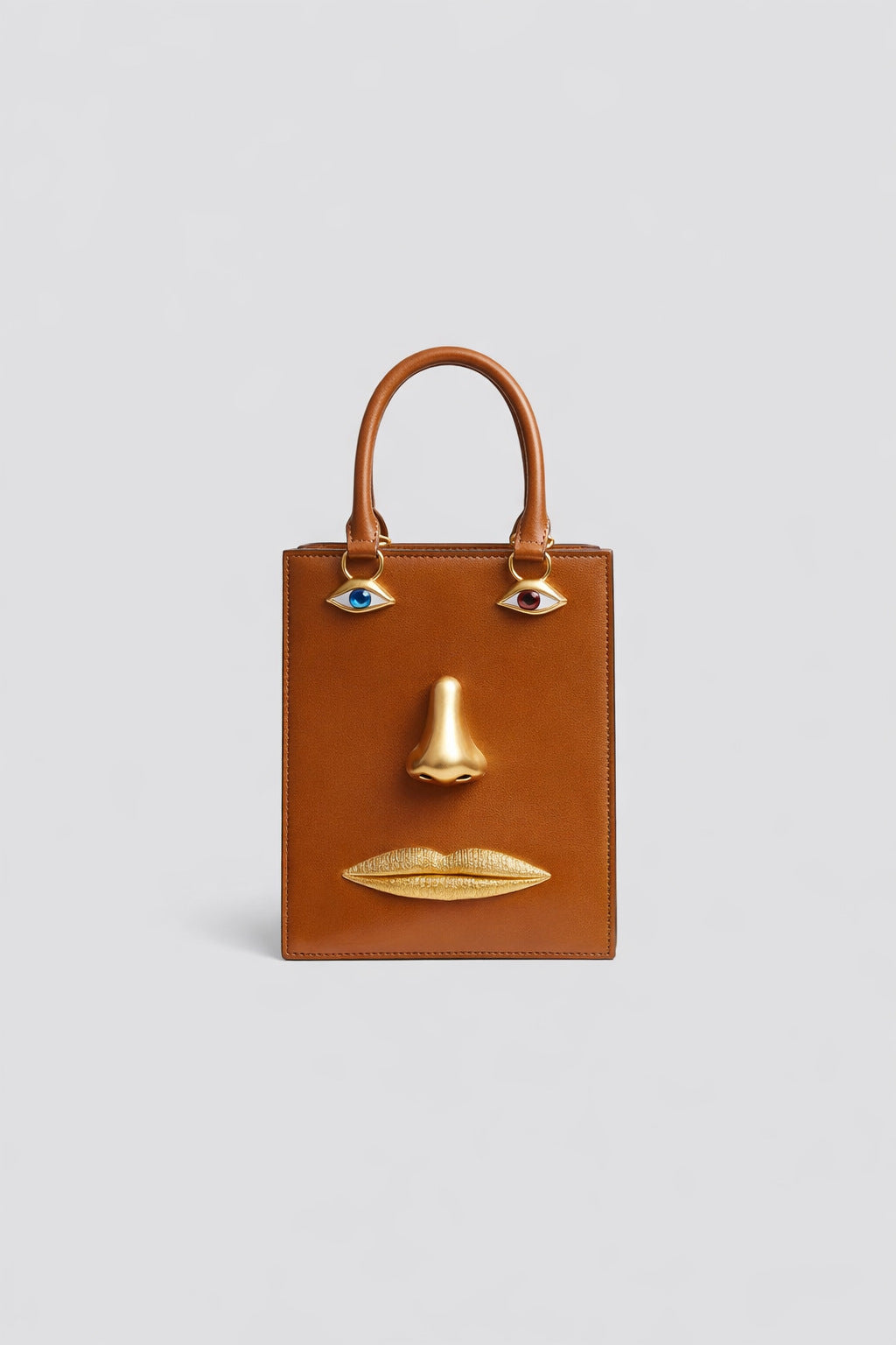 Structured rectangular top-handle bag in tan leather-look finish with gold-tone sculptural face hardware including