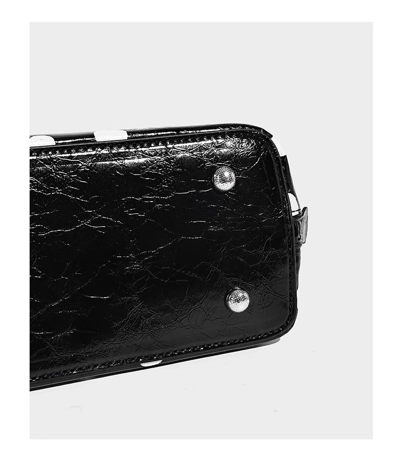 Structured polka-dot Boston bag with glossy crinkled finish, dual top handles, silver-tone turn-lock clasp, and detachable