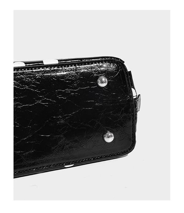 Structured polka-dot Boston bag with glossy crinkled finish, dual top handles, silver-tone turn-lock clasp, and detachable