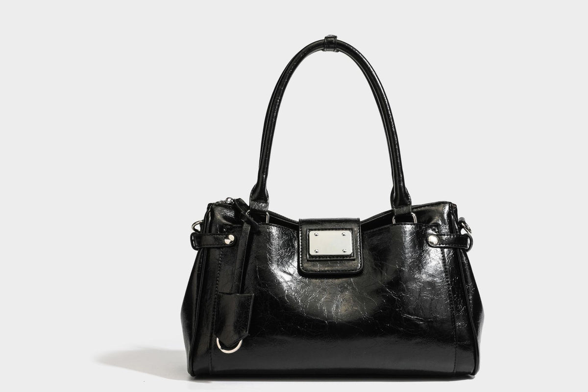Structured glossy crinkled leather-look satchel with double top handles, front metal-plaque tab, silver-tone hardware, and