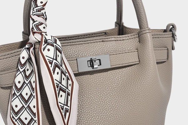 Kleine strukturierte Henkeltasche mit genarbter Oberfläche in Taupe, zwei Tragegriffen, bedrucktem Schalband, Drehverschluss an der Vorderseite und, Detail