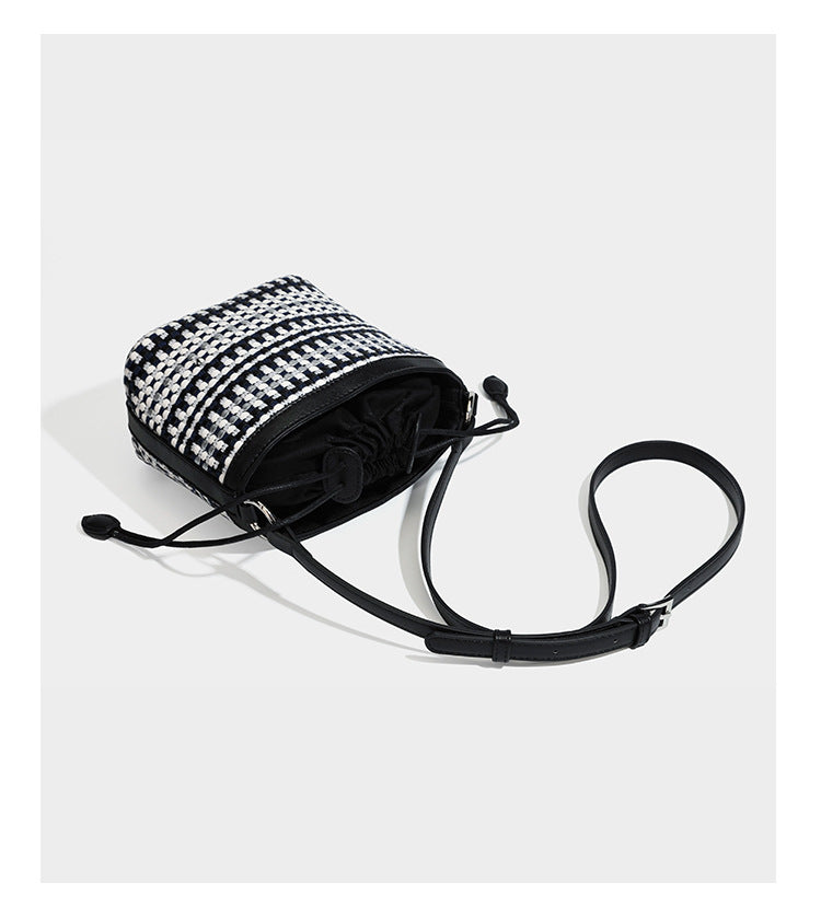 Small structured woven checker bucket bag with braided top handle, drawstring closure, and silver-tone hardware in black