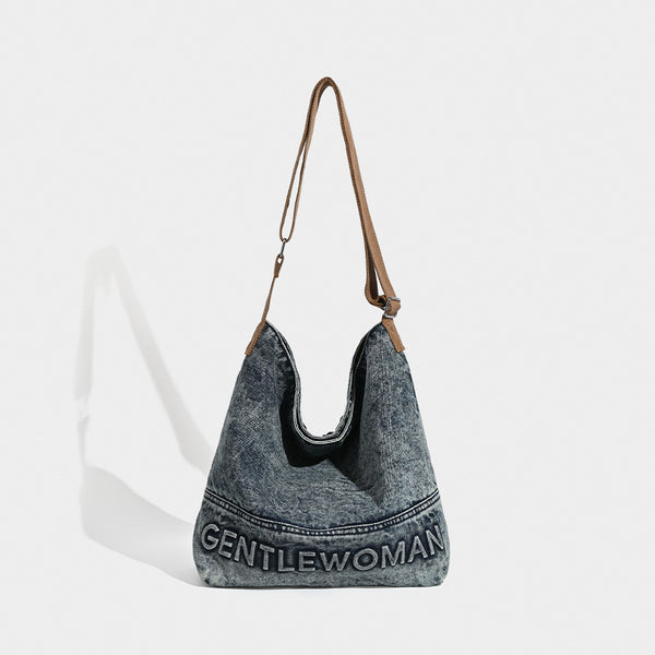 Washed blue denim slouchy open-top shoulder tote bag with tan leather-look adjustable crossbody strap and embroidered, detail