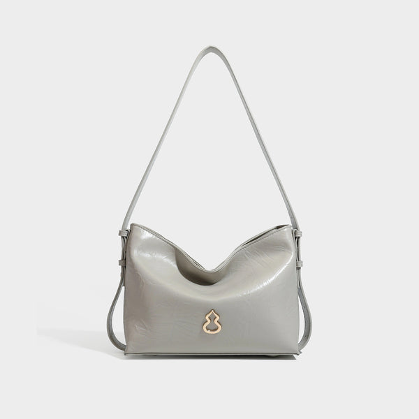 Lässig-sackförmige Hobo-Schultertasche mit offenem oberen Rand in glänzender karamellfarbener Lederoptik, goldfarbenen Logo-Beschlägen und langem verstellbarem