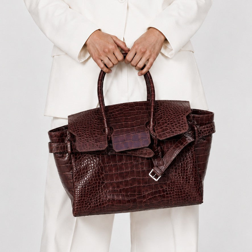 Large structured tote satchel with glossy crocodile-embossed leather-look finish, dual top handles, and metal buckle flap