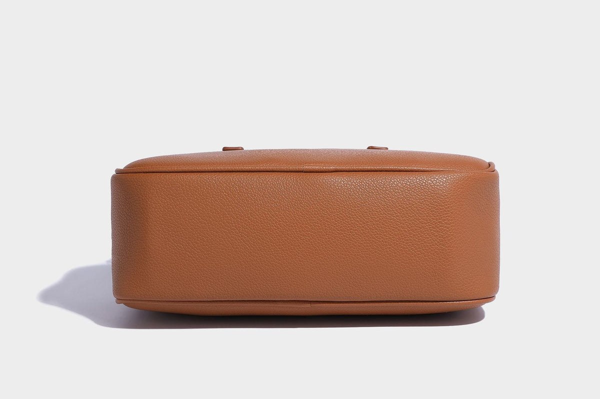 Structured pebbled leather-look Boston bowling bag in tan with blue detachable round mini pouch, dual top handles, and