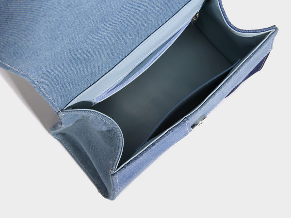 Structured patchwork denim trapezoid satchel bag with frayed panel trim, rounded top handle, and silver-tone hardware, detail