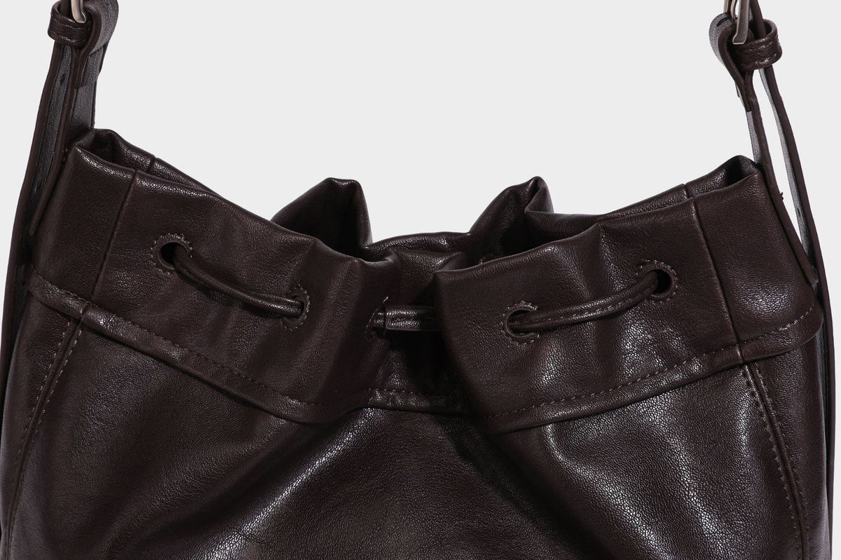 Lässig fallende Beuteltasche mit Kordelzug in dunkler Espresso-Lederoptik, verstellbarem Riemen und Ringbeschlägen aus Metall