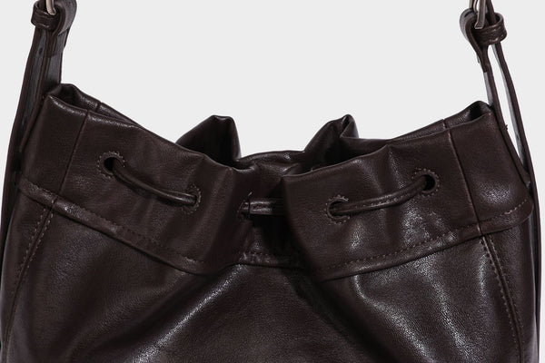 Lässig fallende Beuteltasche mit Kordelzug in dunkler Espresso-Lederoptik, verstellbarem Riemen und Ringbeschlägen aus Metall