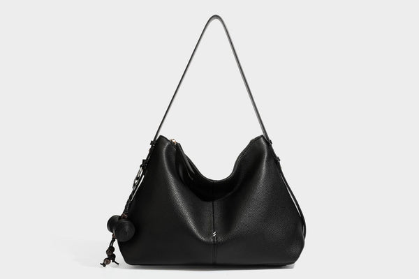 Slouchy hobo shoulder bag with pebbled leather-look finish, zip-top closure, gold-tone hardware, and hanging bead charm