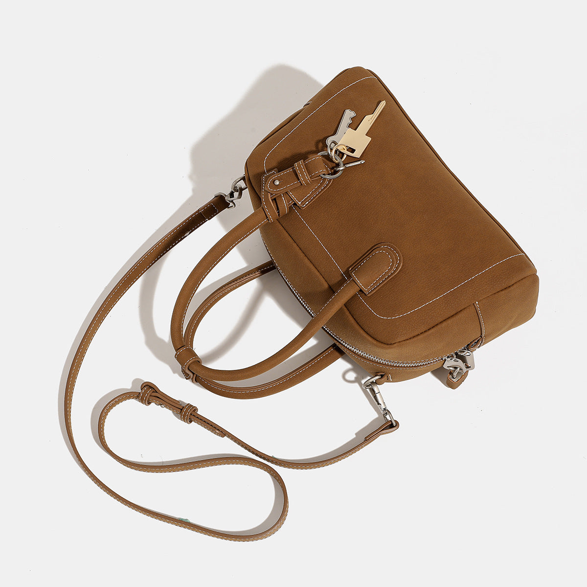Kompakte, strukturierte Henkeltasche mit matter genarbter Oberfläche, geknoteten Doppelgriffen, goldenem Schlüsselanhänger und abnehmbarem, Detailansicht