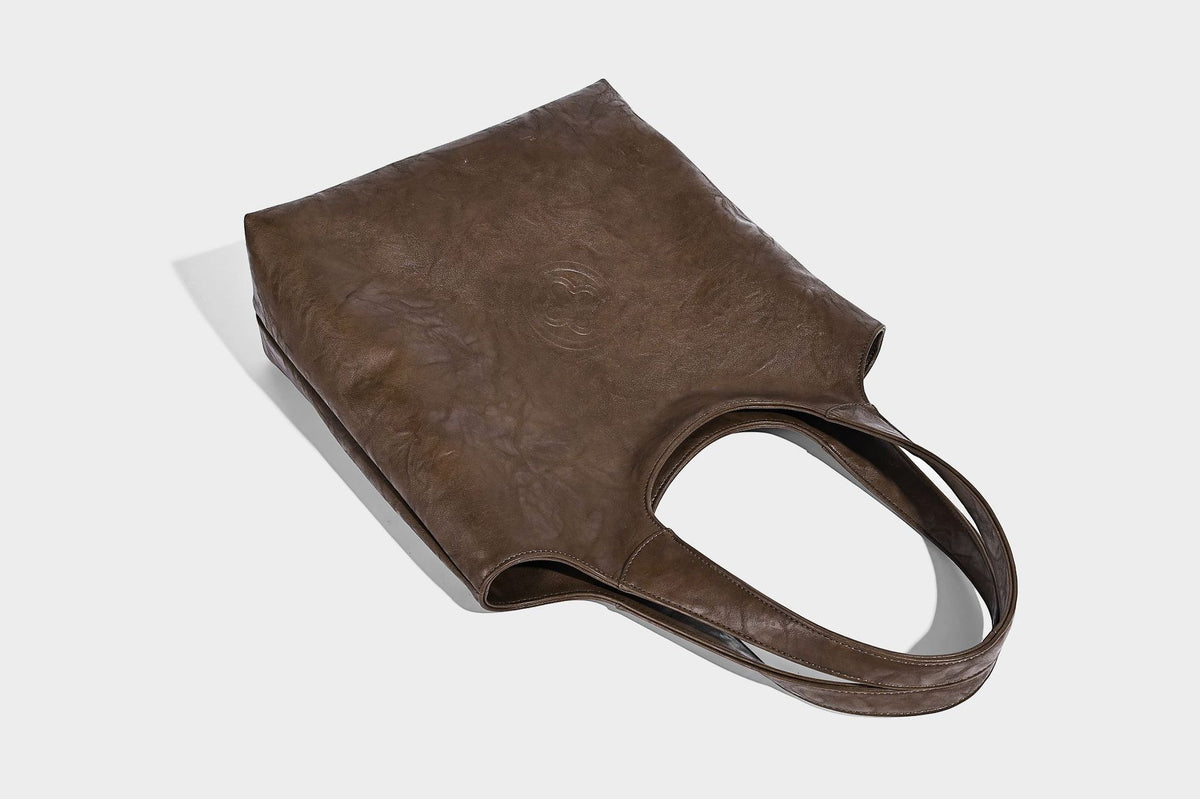 Large open-top tote bag with crinkled leather-look finish, long double shoulder straps, and embossed circular detail on