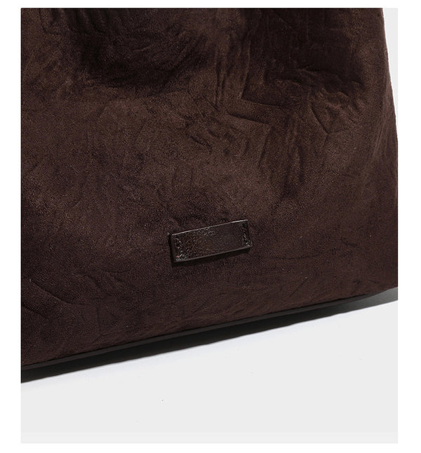 Dunkelbraune, lässig fallende Hobo-Schultertasche mit velourslederähnlich strukturierter Oberfläche, glatter lederähnlicher Paspelierung und Details in Antikgoldoptik, Detailansicht