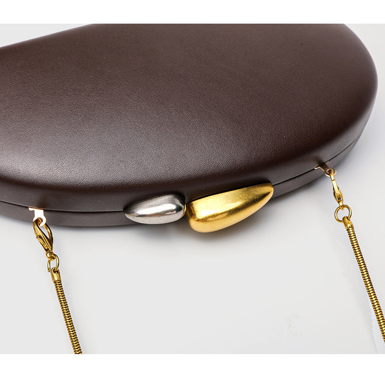 Oval hard-shell crossbody clutch bag with smooth matte leather-look finish and gold-tone snake chain strap, detail view 8