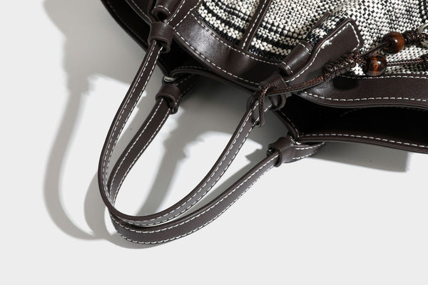 Schwarz-weiße gewebte Trapez-Tote-Bag mit dunklem Lederimitat-Besatz, weißen Kontrastnähten und zwei Henkeln, Detailansicht