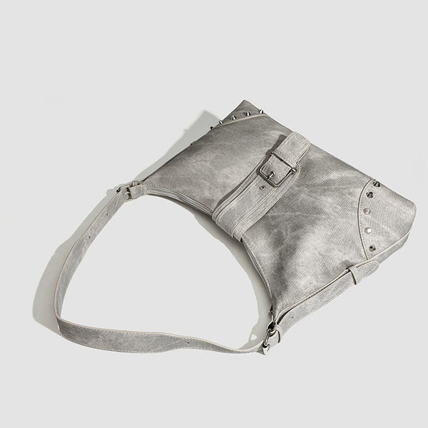 Slouchy trapezoid hobo shoulder bag with distressed textured finish, silver rivet corner accents, centre buckle strap, and
