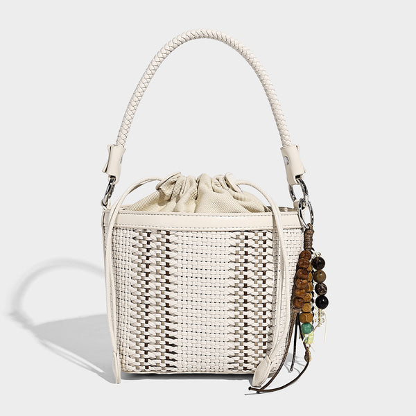 Small woven bucket bag with drawstring top, braided handle, detachable crossbody strap, and silver-tone ring hardware, detail