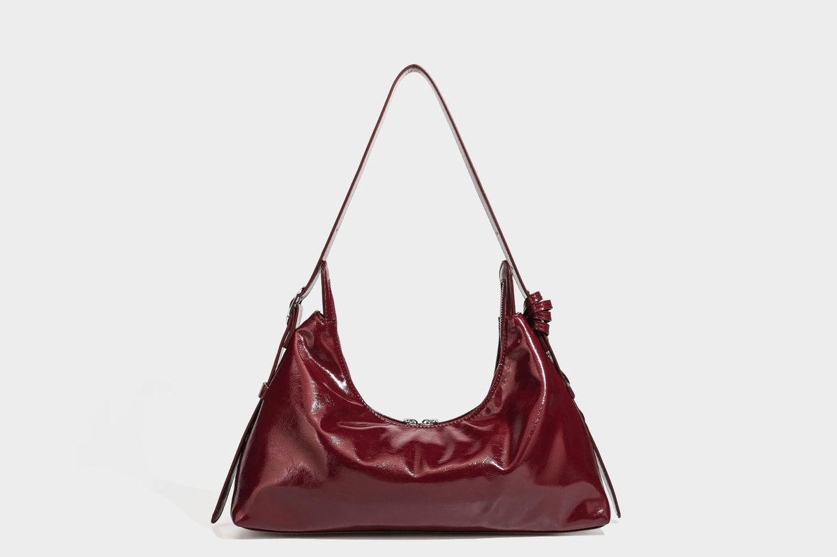 Glossy dark brown hobo shoulder bag with slim strap, front zip pocket, stud detail, and detachable leopard-print heart charm