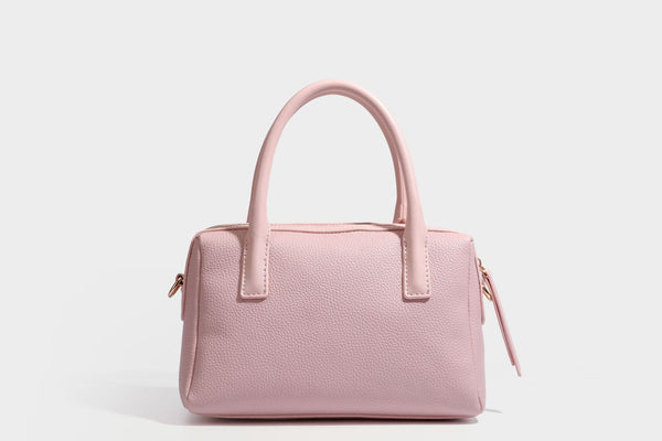 Small structured pillow satchel bag with pebbled leather-look finish, dual rolled top handles, gold-tone gourd emblem, and