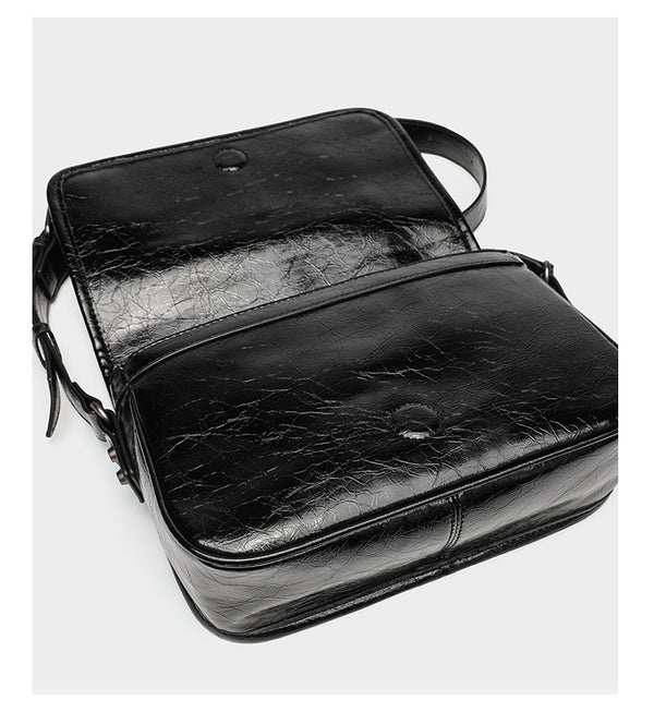 Small structured rectangular crossbody bag with crinkle leather-look finish, front zip pocket, gunmetal stud hardware, and