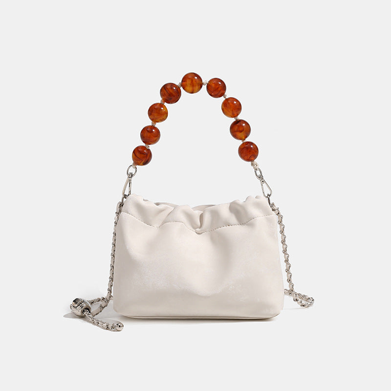 Ruched drawstring bucket bag with amber resin bead handle and silver-tone chain strap, front view