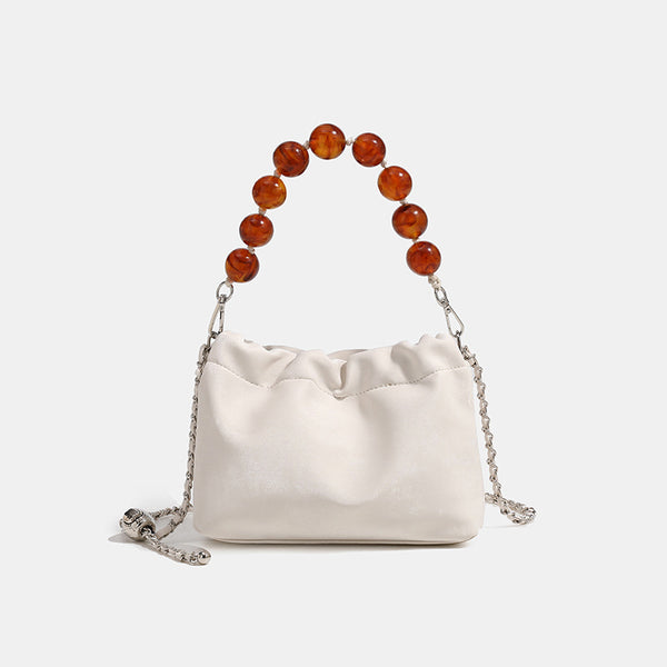 Ruched drawstring bucket bag with amber resin bead handle and silver-tone chain strap, front view