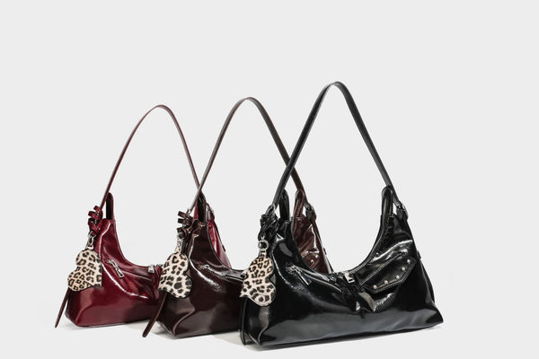 Glossy dark brown hobo shoulder bag with slim strap, front zip pocket, stud detail, and detachable leopard-print heart charm