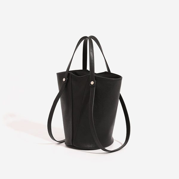 Structured black leather-look bucket tote bag with slim shoulder straps, silver-tone stud hardware, and tapered body, detail