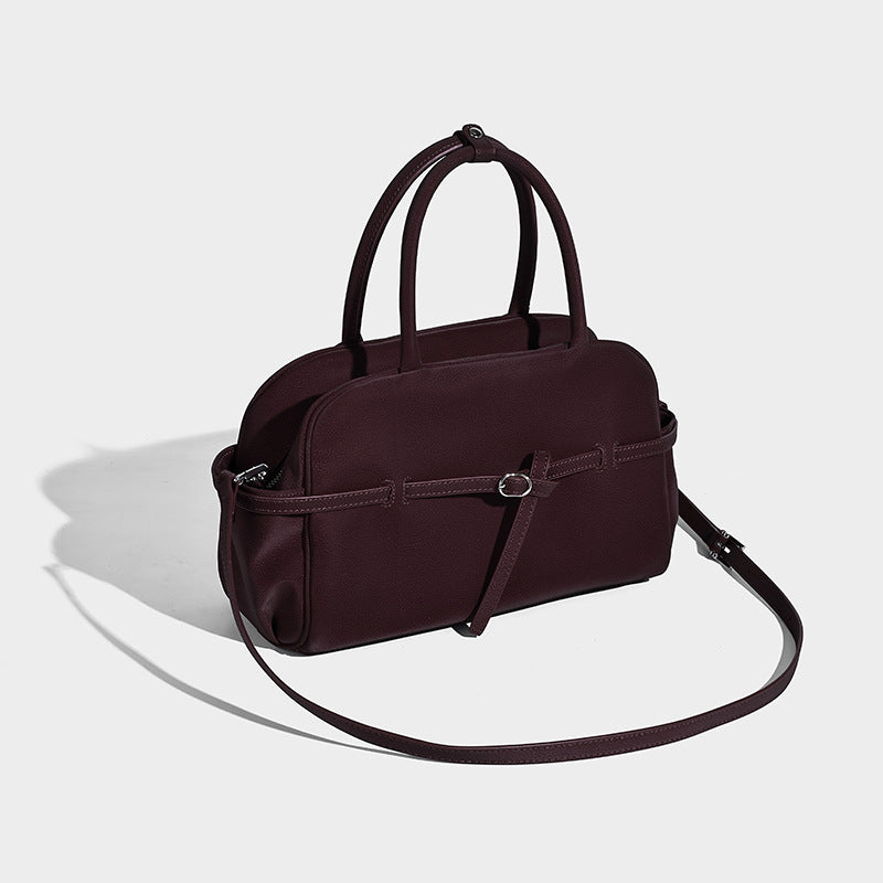 Strukturierte Henkeltasche mit matter, genarbter Oberfläche, umlaufendem Riemen mit Ringbeschlägen, zwei Tragegriffen und abnehmbarem Umhängeriemen