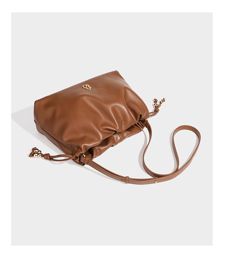 Slouchy ruched drawstring shoulder bag in smooth leather-look finish with gold-tone emblem and slim adjustable strap, detail