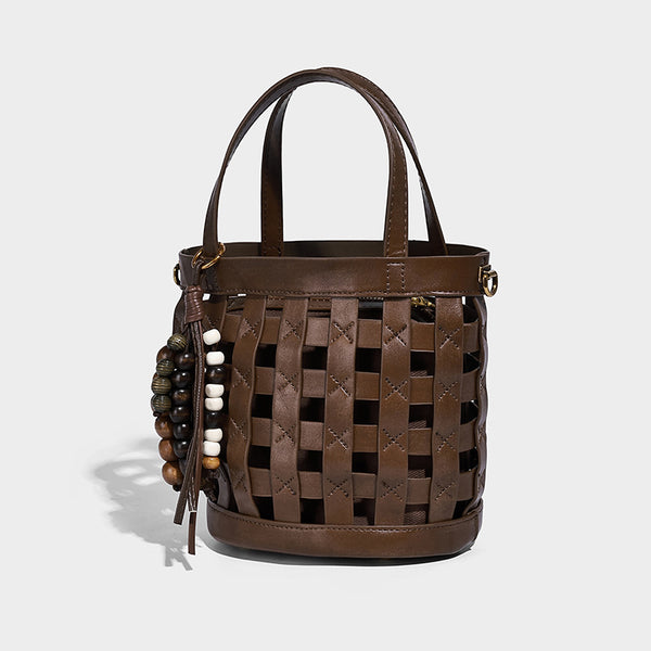 Small woven lattice bucket bag in brown leather-look finish with beaded tassel charm, dual top handles, and detachable