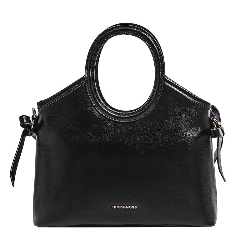 Structured trapezoid tote bag with oval top handle, glossy leather-look finish, side tie details, and gold-tone hardware