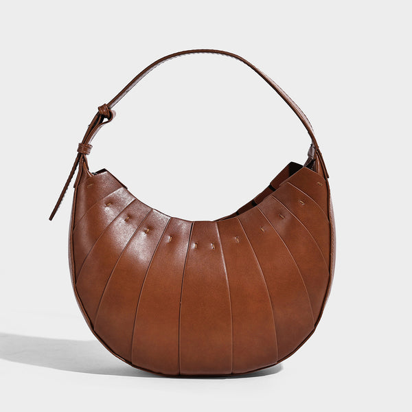 Crescent half-moon shoulder bag with vertical panel seaming, matte-satin leather-look finish, and adjustable gold-tone
