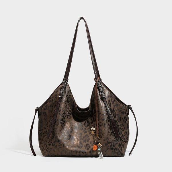 Slouchy leopard-print shoulder tote bag in tan and brown with long double straps, side tie straps, and dangling charm, detail