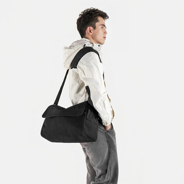 Große Messenger-Bag aus mattem schwarzem Canvas mit Frontklappe, Reißverschluss oben, elastischen Seitentaschen und verstellbarem silberfarbenem