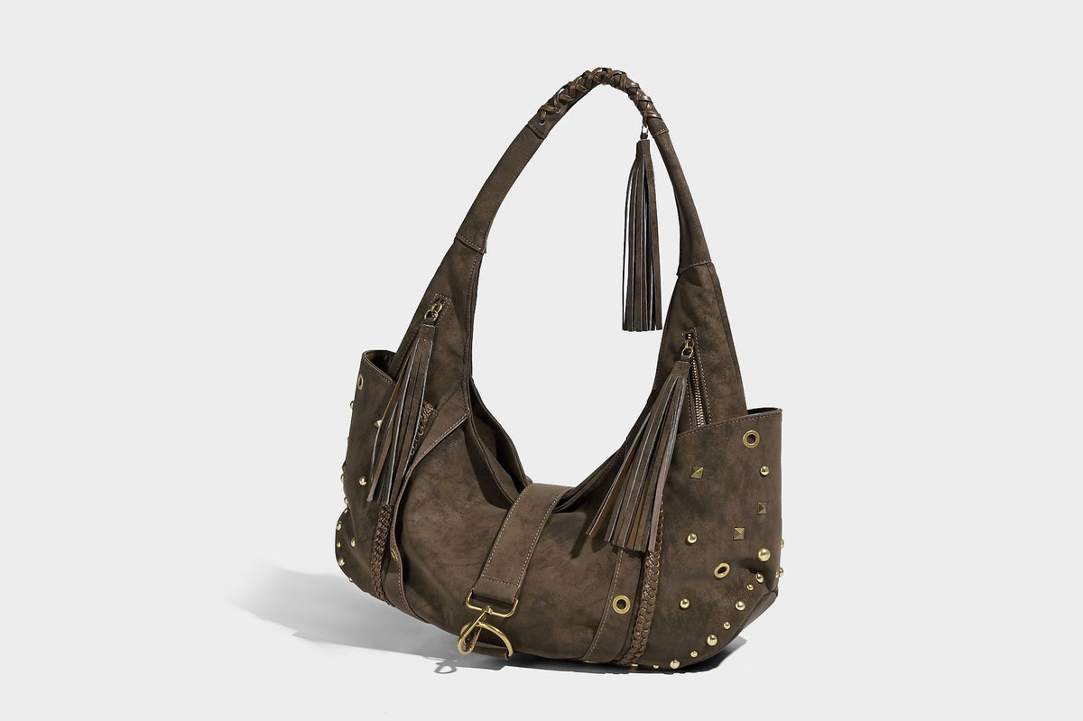 Slouchy crescent hobo bag in matte brown suede-like finish with gold-tone studs, grommets, braided top handle, tassel side