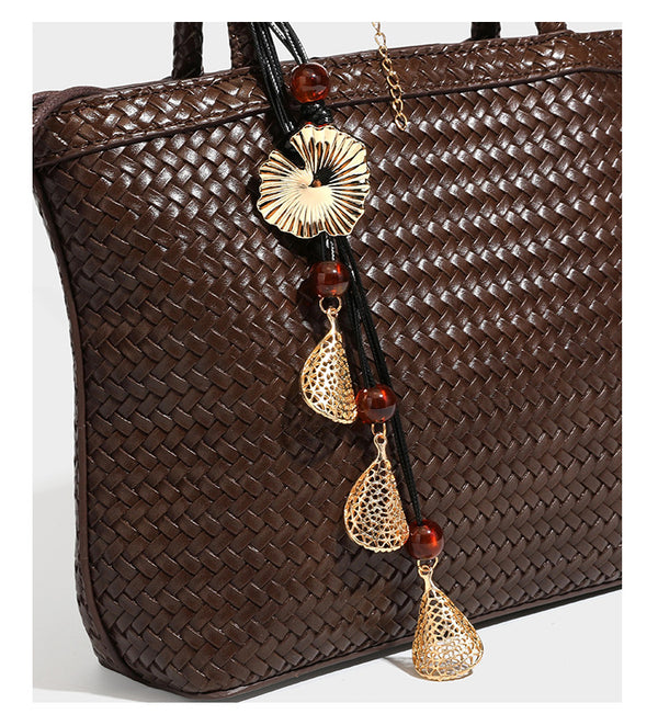 Structured woven leather-look tote bag in dark brown with long shoulder straps, side drawstring ties, and gold filigree