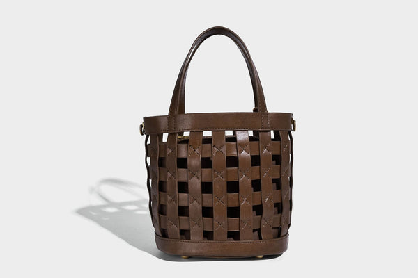 Small woven lattice bucket bag in brown leather-look finish with beaded tassel charm, dual top handles, and detachable