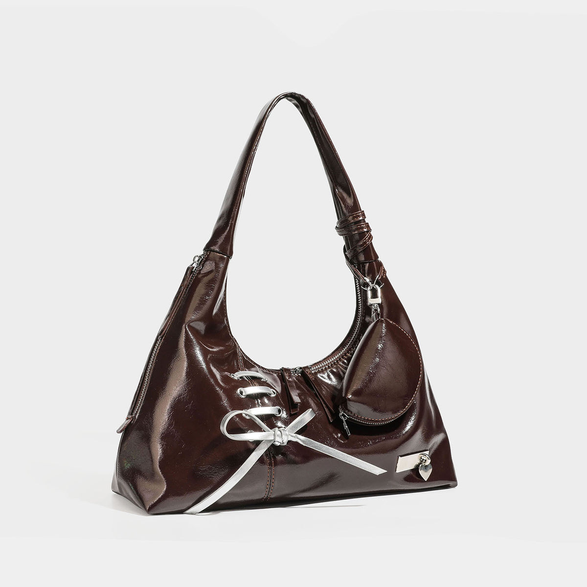 Slouchy hobo shoulder bag in glossy leather-look finish with silver lace-up eyelets and ribbon bow on the front panel, front