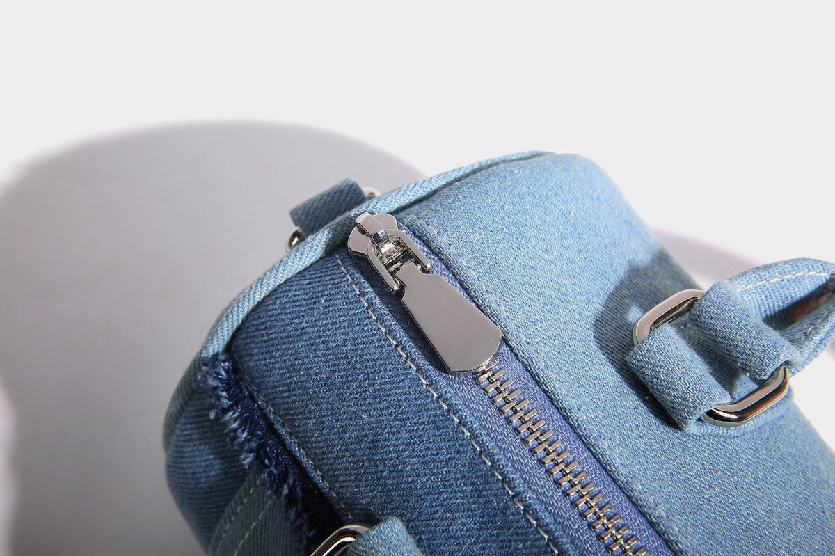 Mini barrel handbag in light and dark denim patchwork with frayed seam trim, dual top handles, top zip closure, and, detail